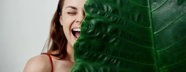 joyful woman covers her face with palm leaf Exotic close-up joyful woman covers her face with palm leaf Exotic close-up. High quality photo