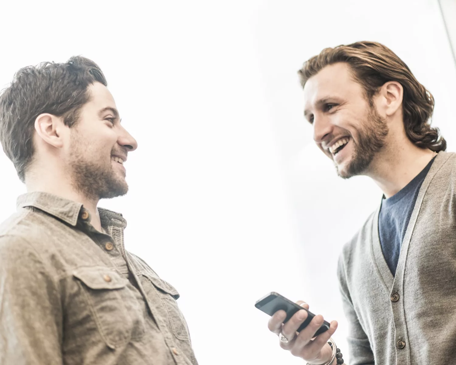 Jersey City,USA,Two men smiling, one holding a smart phone. Jersey City,USA,Two men smiling, one holding a smart phone.